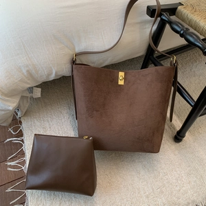 Detail of dark brown suede tote bag with golden twist lock and small inner pouch
