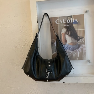 Detailed view of black hobo bag texture with metallic star ornament and leather strap