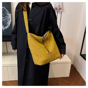 Close-up of ginger yellow plush crossbody bag with soft fuzzy texture and woven label