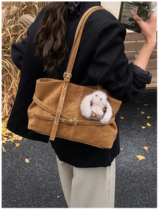 Detailed view of brown suede tote bag with decorative buckles and plush bunny charm