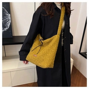 Macro detail of mustard yellow plush knit crossbody bag with drawstring and leather tag