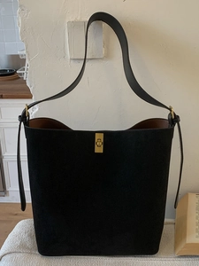 Minimalist black suede bucket bag with gold twist lock and leather shoulder strap for women