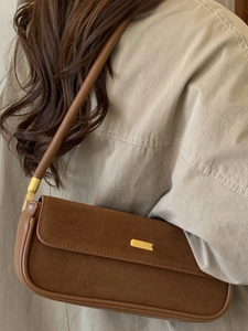 Braune Retro-Achseltasche aus Wildleder mit Goldschnalle am Modell in weicher Ästhetik