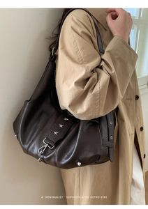Close-up of retro brown leather tote with silver star studs and lobster clasp detail