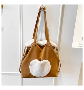 Dettaglio della borsa vintage in pelle scamosciata marrone con cuore in pile bianco e lacci