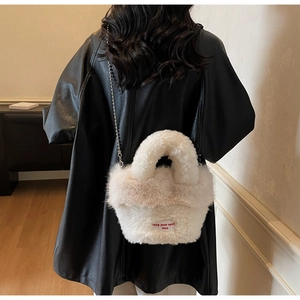 Detail der flauschigen cremeweißen Beuteltasche mit rotem Patch und silberner Kugelkette