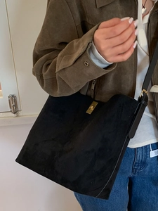 Minimalist black suede bucket tote bag with gold metal buckle and slender shoulder strap