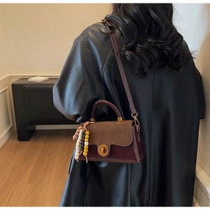 Close-up of vintage mini crossbody bag with metal turn-lock and beaded pendant detail