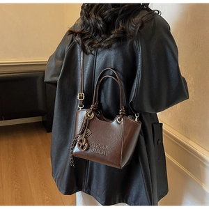Sac seau vintage en cuir marron ciré avec logo embossé et pendentif tissé détaillé