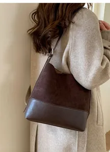 Deep brown patchwork shoulder bag in matte suede and smooth leather on a model
