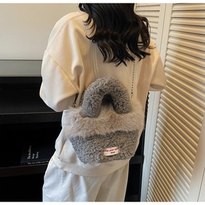 Detailansicht einer grauen flauschigen Plüschtasche mit silberner Kugelkette am Modell