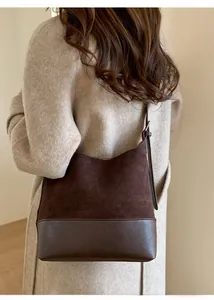 Detail of dark brown patchwork shoulder bag with adjustable strap on a model