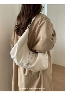 Detail of hobo bag featuring silver star rivets and soft cream leather texture on shoulder