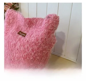 Detail of pink plush bucket bag showing soft faux fur texture and leather brand label