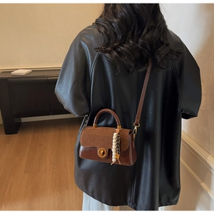 Detail view of a vintage brown crossbody bag with suede patchwork and beaded tassel charm
