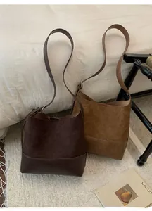 Detailed close-up of dark brown and caramel suede bucket bags in a cozy autumn setting