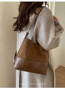Detailed side view of a brown patchwork leather tote bag on model for retro commute style
