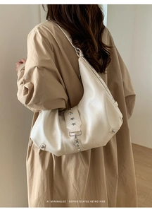 Detail of cream leather tote showing side star rivets and slouchy shoulder strap