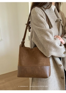 Side view of a brown suede and leather patchwork tote bag on a model in wool coat
