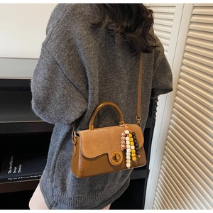 Close-up of retro brown bicolor handbag with metal lock and rainbow beads on a model