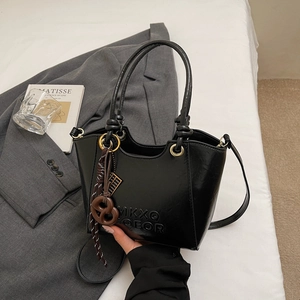 Détail du sac seau noir avec poignée nouée et texture en relief 3D sur le cuir