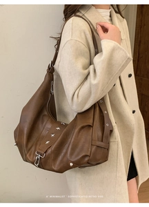 Detail of brown vintage crescent tote bag featuring silver star rivets and metal hook accessory
