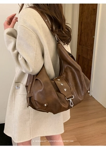 Detail of dark brown vintage faux leather tote bag with silver star rivets on the shoulder strap