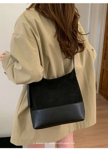 Minimalist black tote bag in spliced suede and leather material on a street-style model
