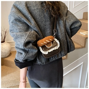 Detail of brown vintage crossbody bag with white lace trim and plush bear charm