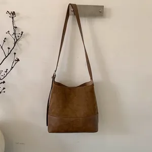 Detailed view of brown suede bucket bag with adjustable strap and metallic buckle