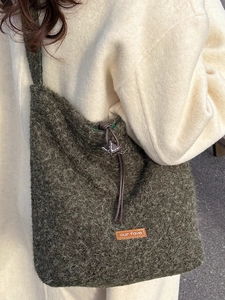 Olive green faux fur crossbody bag with drawstring closure and vintage leather patch