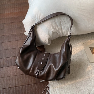 Close-up of dark brown vintage leather tote with silver star rivets and soft texture