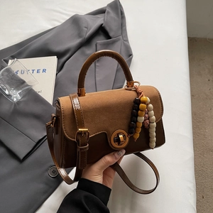 Detail of a brown vintage crossbody bag with a round twist lock and ethnic wooden beads