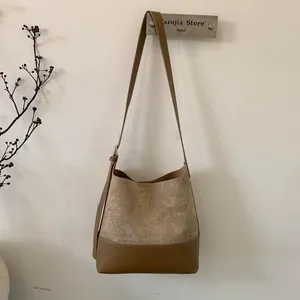 Detailed view of brown bucket bag featuring faux suede and smooth leather patchwork design