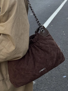 Deep brown quilted suede bucket bag with silver chain strap shown from a 45-degree angle