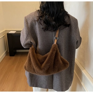 Détail du sac hobo en peluche marron foncé avec bandoulière en cuir porté à l'épaule