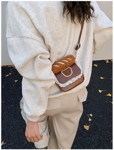 Brown mini crossbody bag featuring white lace trim, bear embroidery, and bread plush toy