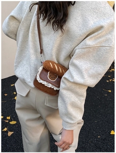 Detail of a brown mini crossbody bag with white lace trim and cute bear patch on the flap
