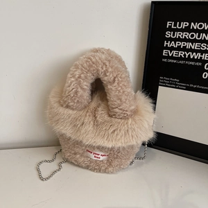 Detail der beigen Kunstpelz-Handtasche mit Spirit-Free-Aufnäher und silberner Kette