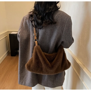 Détail d'un sac bandoulière en fausse fourrure marron porté sur un blazer gris chic