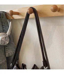 Detail view of a long adjustable smooth leather shoulder strap on a brown bucket bag