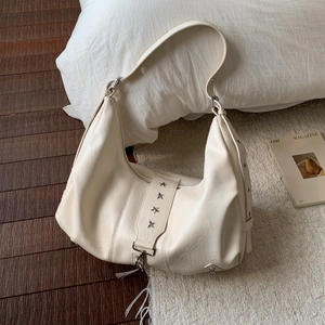 Detailed view of cream hobo bag featuring silver star rivets and soft leather texture