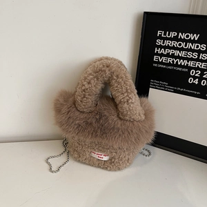 Detail einer flauschigen braunen Kunstpelztasche mit weißem Webetikett und Metallkettenband