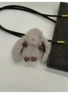 Nahaufnahme eines flauschigen grauen Hasen-Anhängers an einer braunen Ledertasche