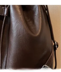 Close-up of deep brown leather texture and metal buckle on retro drawstring bucket bag