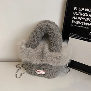 Nahaufnahme einer grauen Plüschtasche mit Kunstpelzbesatz und dekorativer Perlenkette