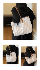 Detail of spacious canvas tote bag with NK letter prints and brown leather handles