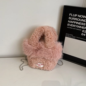 Detail der rosa Plüsch-Mini-Handtasche mit weißem Etikett und silberner Perlenkette