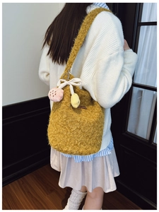Detailed back view of a fuzzy yellow knit hobo bag with a white bow and plush charms