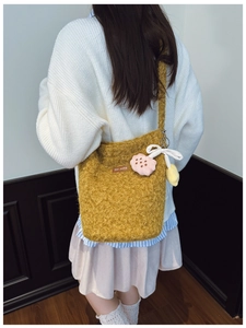 Detail view of ginger plush bucket bag with flower charm and ribbon on shoulder
